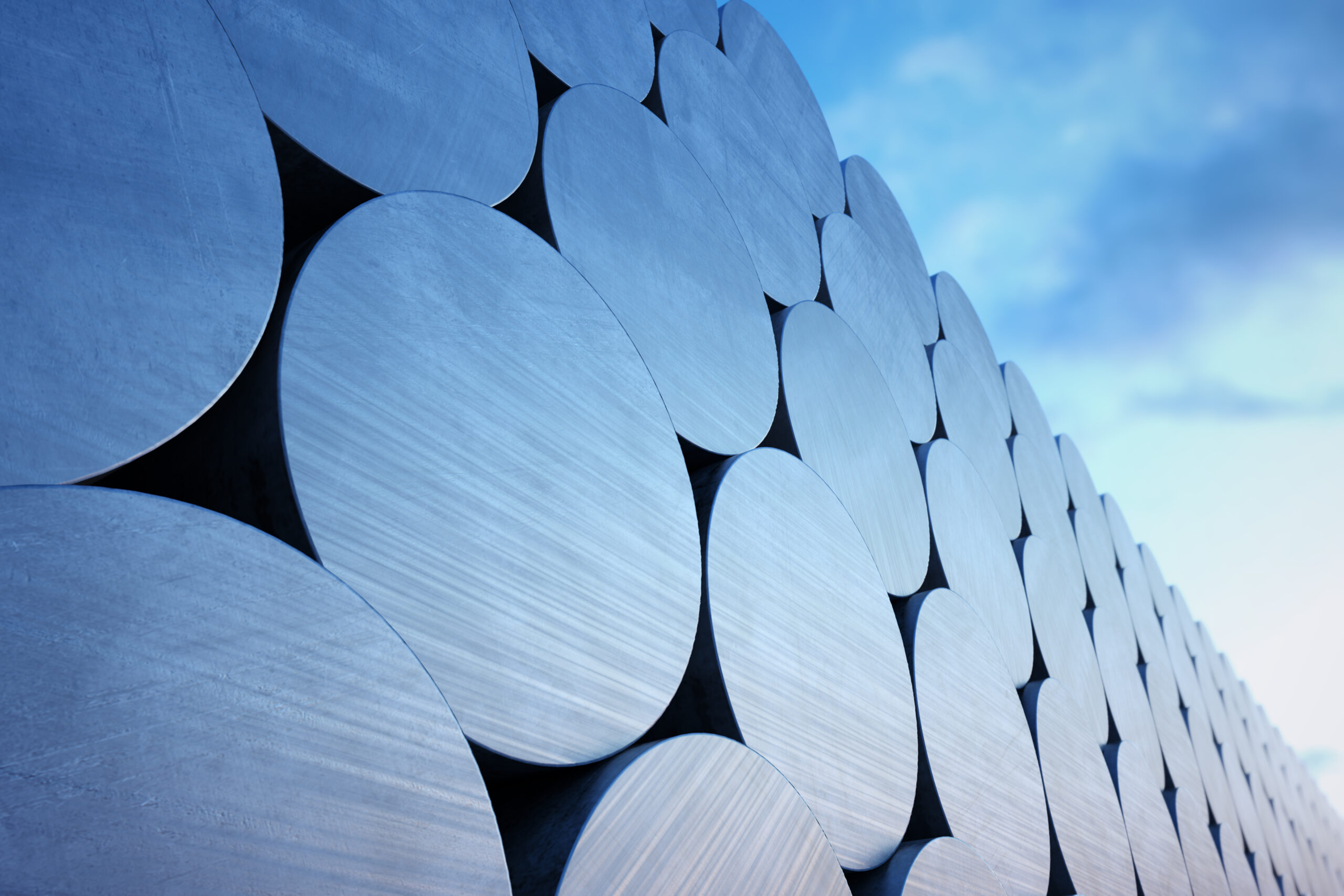 Stack of aluminium billets on a cloudy sky background. Suitable for any industrial related purposes.